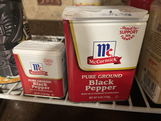 Two tins of McCormick-brand ground black pepper, one much bigger and one much smaller.