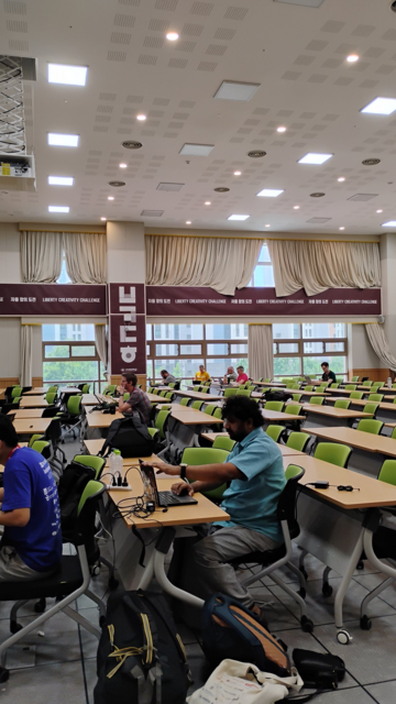 A large hall with people sitting in front of laptops