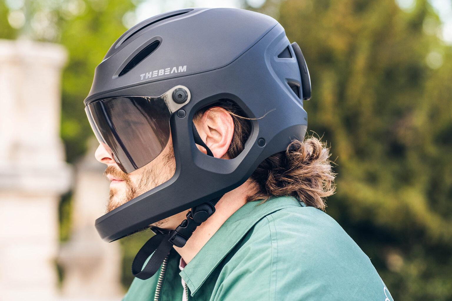 Photo du casque sur quelqu'un. C'est un casque noir, intégral, avec une mentonnière et une visière noire.