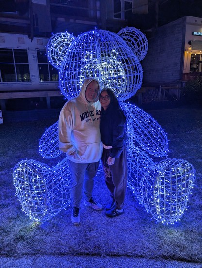 A photo that a friend of mine took with my Pixel 8 Pro of my wife and I standing in front of a bear that's lit up with Christmas lights. We were in Myrtle Beach, SC at the time.