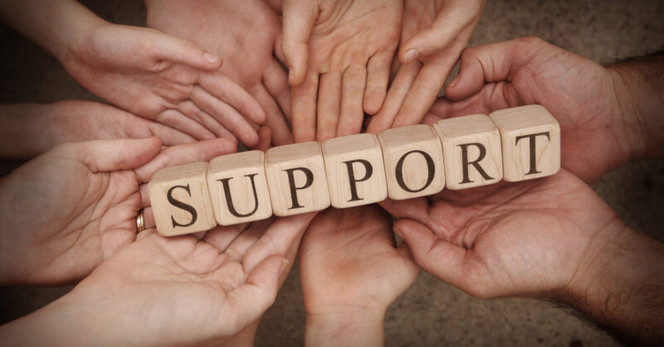 An image with a bunch of human hands holding wood blocks that spell out the word SUPPORT.