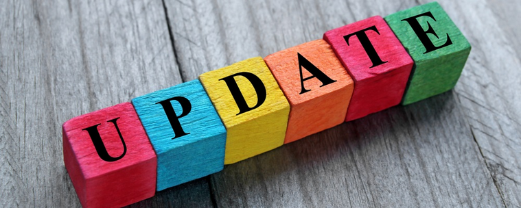 An image that says the word UPDATE in different colored blocks that are sitting on a wooden table. 