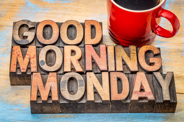 An image that says Good Morning Monday carved out in wood blocks. There's a red coffee cup on the top right with some coffee in it.