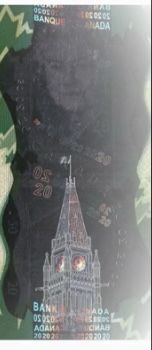 Close-up of Canadian $20 bill, on which Elizabeth II’s face floats menacing and huge above the parliament building 
