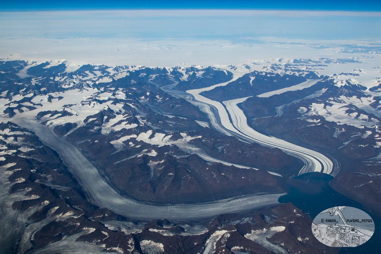 Top down View of 2 glaciers flowing into their respective bays. It’s very good visible where the ice flows from the central shield over the mountains.