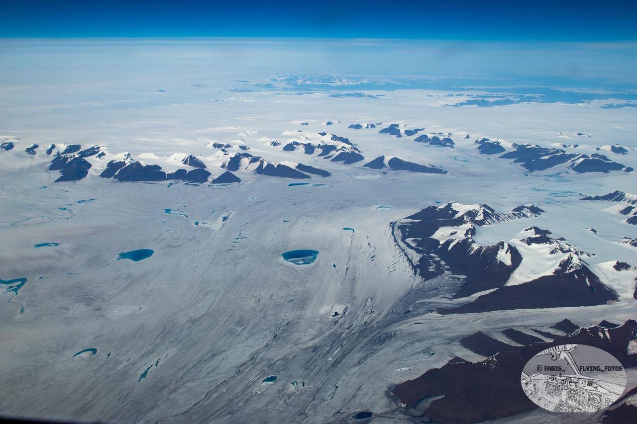 Top down View on the central iceshield with some azure blue lakes with a mountain ranges on one side.