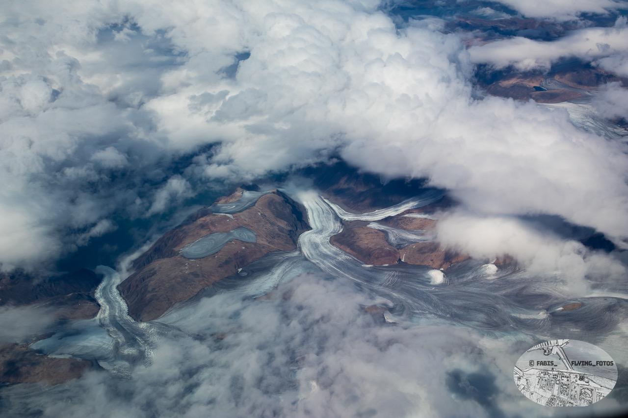 Top down View of mountains and clouds and glaciers.