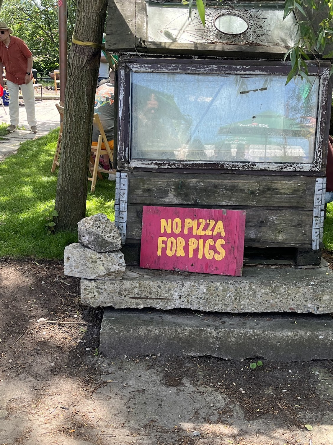A yellow on red handpainted sign that reads "No Pizza For Pigs."