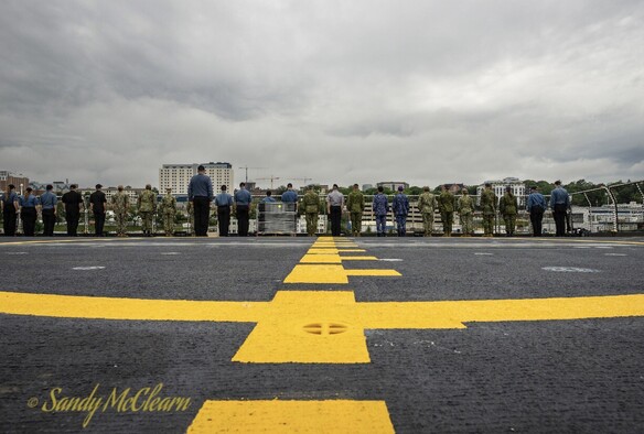 Crew lining the ship’s rail on flight deck during departure. 
