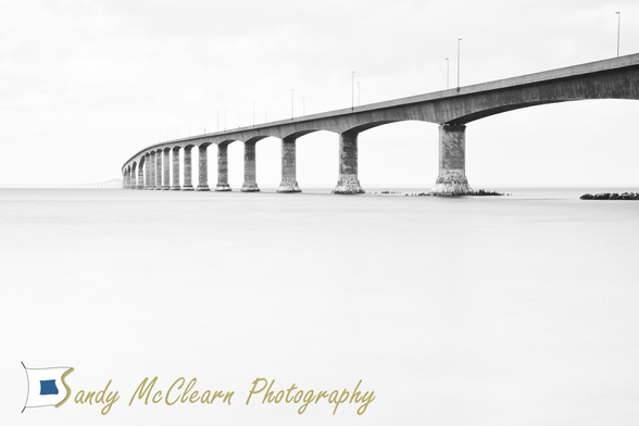 Bridge extends into the distance over flat water. 