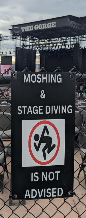 A warning sign saying "Moshing & Stage Diving is Not Advised"

In the background, THE GORGE amphitheater sign rises behind