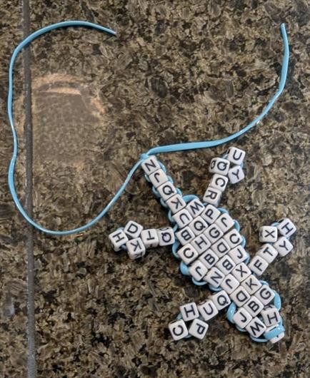 A beaded keychain in the form of a lizard or gecko

But all the beads are small square letter-cubes. 

It looks like a crossword puzzle origami-ed itself into a lizard