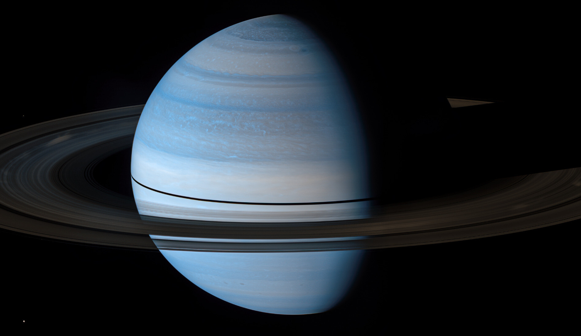 Saturn appears blue in this near-infrared false color. The rings, facing the Sun edge-on, are dark.