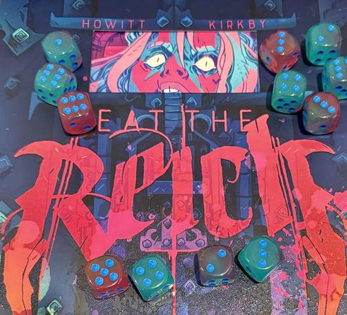 A dozen dice arranged on top of, and matching the bright colors of the book cover for Eat the Reich