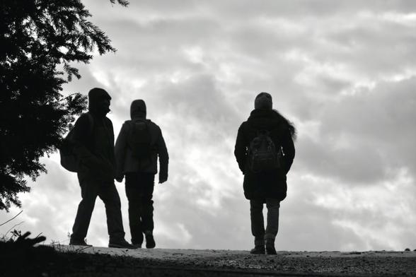 Three people are walking on a street while the sky is cloudy.

Drei Personen gehen bei bewoelktem Himmel auf einer Strasse spazieren.