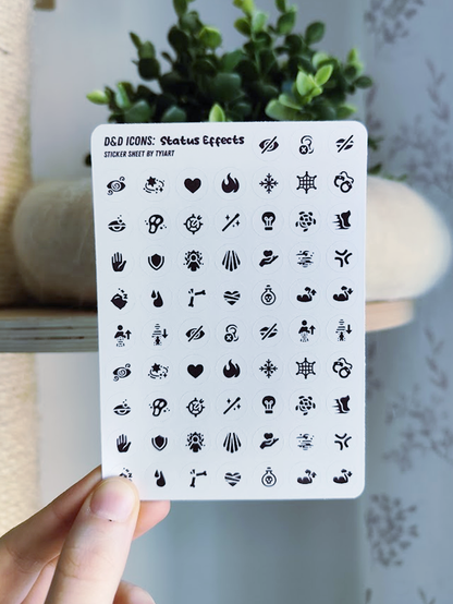 hand holding up a white sticker sheet with tiny black icons showing different status effects