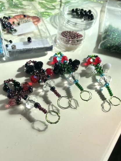 Four little wands with a loop at the end, made of metal wire and covered in beads. The wands have three beaded loops at the top and a longer stem