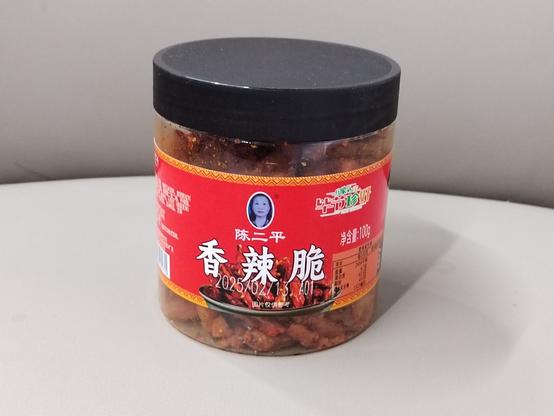 This is a 100g jar of the stuff (effectively a sampler size; a more usual size is 200-300g) with its black lid, transparent body, and red label with a picture of the food behind its text.  The brand is 陈二平 (Chén Èrpíng).