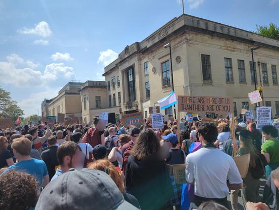 Photo of huge crowd of people with trans rights flags and placards in front of Oxford court building.