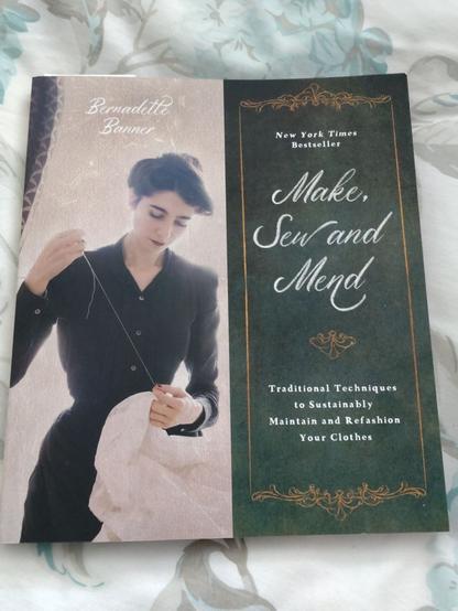 Photo of a book cover, with an elegant lady-type hand sewing next to text; Bernadette Banner, Make, Sew and Mend, Traditional Techniques to Sustainably Maintain and Refashion Your Clothes.