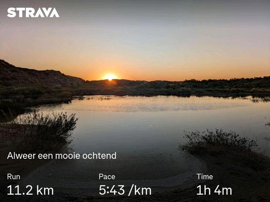 The sun rises over a pond in the dunes. The water reflects the colors in the sky
