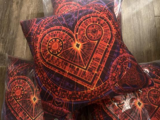 Closeup on pillow with Radiant Heart art design - a Valentine heart done in the complex Geometron graphic style, in reds with yellow highlights and purple/black background