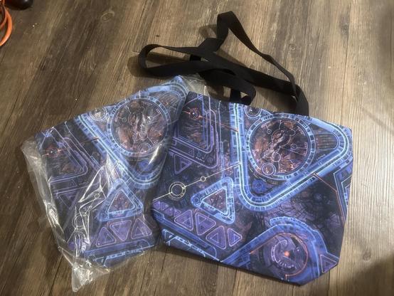 Two 15" tote bags with my art on them - complex blue, white and purple rounded-triangle line art over mostly black space background with orange-red nebula bits.