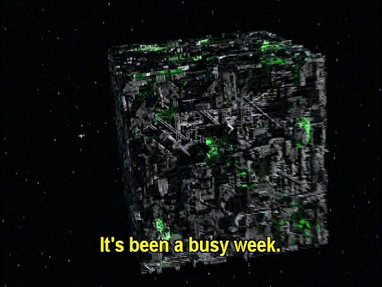 A Borg cube is pictured in space. Just sitting there. I don't think it's at warp because the stars aren't long lines, just spots. Closed caption reads, "It's been a busy week."