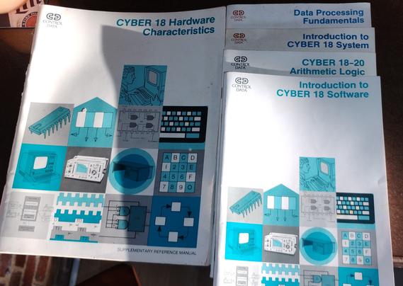 A stack of instructional documents, mostly "learning guides" and one " supplementary reference manual" for the CYBER 18 system by Control Data. The manuals are delightfully 1978 in their design, with copious teal being employed
