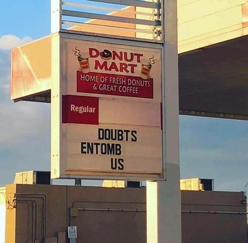 a photo of the sign of a Donut Mart ("home of fresh donuts & great coffee")

that reads "DOUBTS ENTOMB US"