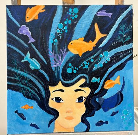 A portrait of a girl in the ocean. Fish are swimming through her hair.