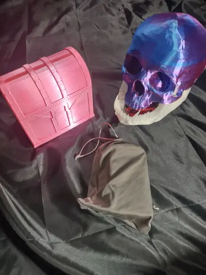 picture of my three main tarot deck containers. One hot pink treasure chest, one purple skullm and one grey drawstring bag