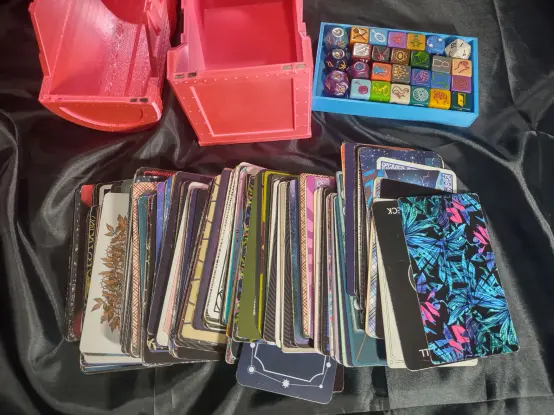 the hot pink chest opened. The dice tray holding the Seasons set of publishing goblin oracle dice is shown, as is my magpie deck, face down, and splayed so you can see the various card backs