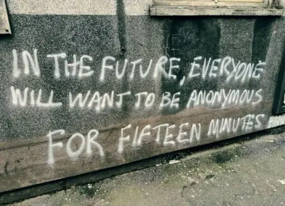 A photo of a graffiti quote on a grey concrete wall that reads "IN THE FUTURE, EVERYONE WILL WANT TO BE ANONYMOUS FOR FIFTEEN MINUTES."