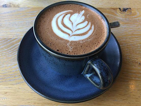 a blue cup filled with mocha and coffe art