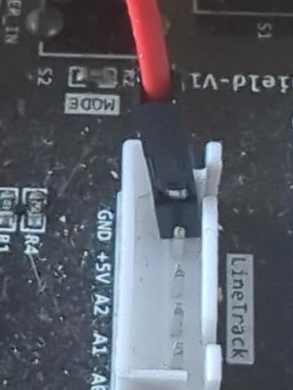 A red wire with a female dupont connector on the end, plugged in to a connector on a circuit board.  The wire connection is loose, leaning to one side.