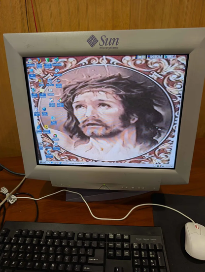 a computer with a sun CRT monitor displaying a windows 95/98 desktop with jesus as the wallpaper