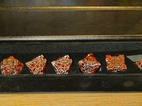 Close up of engraved metal dice with red splatter effect in a long case