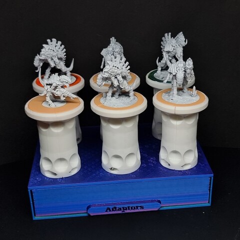 Six white painting handles on a blue box with a drawer in it holding the base adapters