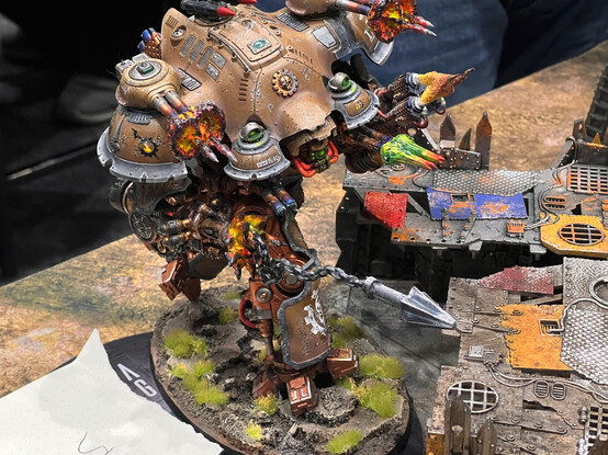 A painted Imperial Knight Valiant from Warhammer 40k. The owner has put in extra effort with modelling, showing the Knight mid-stride as it actively fires the harpoon from its gun. 3d printed muzzle flashes and missiles fire out from the cannons.