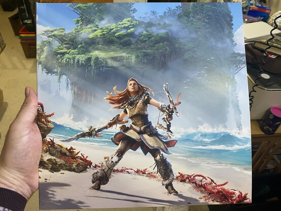 Cover of album, showing Aloy from Forbidden West looking badass with her bow and spear, standing on a beach with her hair whipping around her.