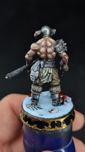 Slaughterpriest miniature standing on a snow base with two bloody axes 