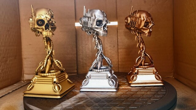 Three warhammer forty thousand servo skull trophies. One in gold one in silver one in bronze