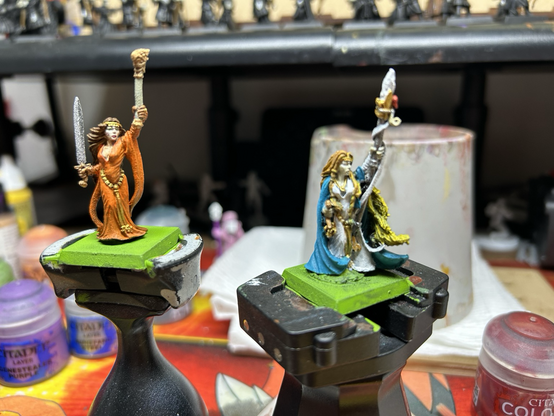 Two Damsel minis for Warhammer The old world, one in orange dress and the other a blue cloak and white dress. Both are armed with magical items and swords.
