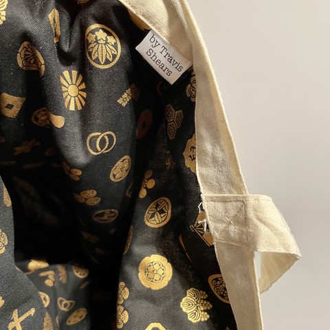 Close up on tag on inside of tote bag that reads: by Travis Shears 
