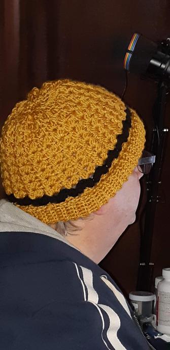 My husband's profile facing to the right. He is wearing a dark blue jacket and is wearing the tuque I made him. It's in a rich carmel color with black hearts around the first couple of rows. The hat has a ribbed edging around the temples.