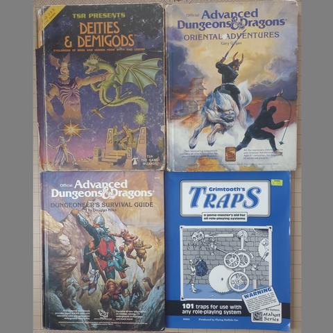 Advanced Dungeons & Dragons 1st Edition Deities & Demigods: A huge human-looking god with a winged helmet has his hand around the throat of a winged serpent with arms holding a two-headed axe.

Oriental Adventures: A katana-wielding samurai riding a white ki-rin (a creature resembling a fluffy dog with hooves) fighting a ninja wielding a chain-based weapon ending in a nasty hook. 

Dungeoneers Survival Guide: An adventurer with a metal helmet is climbing a sheer cliff. He is beset by small flying humanoids appearing from caves in the rock. A halfling clings to his leg, defending themselves with a dagger.

Grimtooth's Traps: A person is arming a wicked-looking trap consisting of gears, weights, and pulleys. 