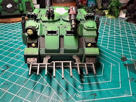 The front of the rhino. The main armories are green. It has bright yellow headlights and a spotlight. On the left cupola are twin linked bolters; on the right cupola is a heavy flamer. The heavy flamer is red. Accent armor is black. 