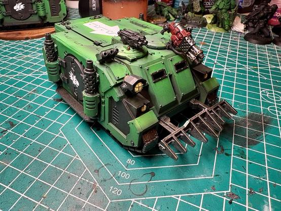 The left front side of the rhino. The spotlight casing is black. The heavy flamer on the right cupola is red; the twin linked bolters are black. The salamander sigil is white and just visible on the left side door. The white arrow, representing tactical squads, is visible on the top hatch. 