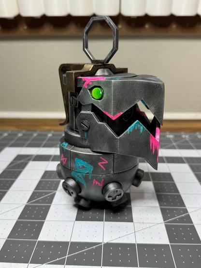 A 3D printed “Chompers” prop (grenade and bear trap combo) from League of Legends/Arcane. Has some neon “Jinx” style graffiti painted on it as well. (Front side view)